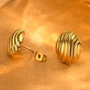 Macro view of gold shell textured stud earrings with a glossy ribbed metal finish