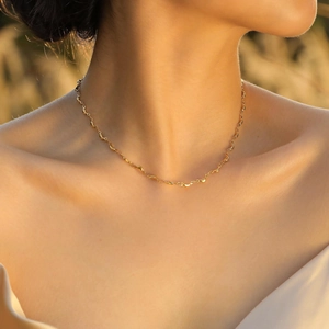 Collana a girocollo in acciaio inossidabile dorato indossata da una modella al sole caldo