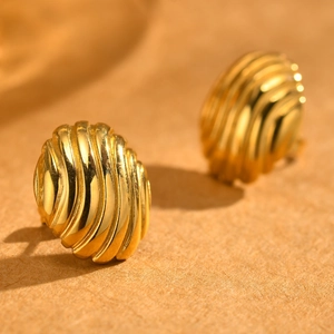 Macro shot of golden stainless steel shell-textured stud earrings with ribbed details