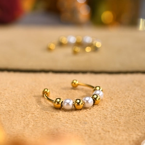 Macro detail of gold-plated beaded open ring with alternating white faux pearls