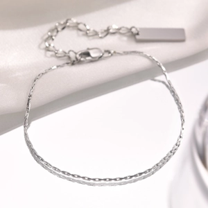 Detailed close-up of a silver minimalist chain bracelet with a polished rectangular pendant