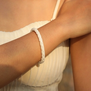 Gros plan d'un bracelet en cuir tressé blanc au poignet avec une texture tissée élégante