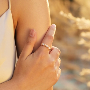 Minimalist gold beaded ring for women featuring white pearls on a model's hand