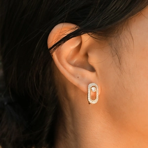 Close-up of golden oval earrings featuring sparkling zircons and a moving center stone
