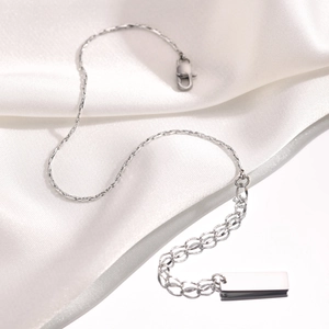 Detailed macro view of square link necklace with extension chain on white silk fabric