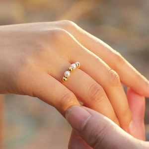 Elegant gold stainless steel open ring with alternating white pearls on woman's hand