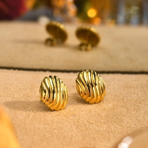 Macro shot of gold-plated stainless steel earrings with spiral wave pattern texture