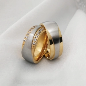Detail of two-tone stainless steel couple rings with brushed finish and zircon inlay