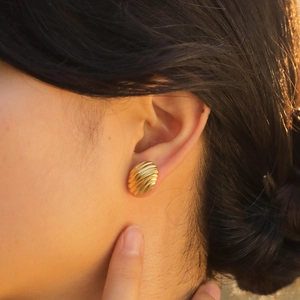 Golden oval corrugated shell pattern earrings in stainless steel on female model
