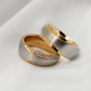 Close-up of two-tone stainless steel couple rings with zircon inlay and brushed finish