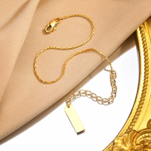 Close-up of golden square link chain necklace with lobster clasp and rectangular plate