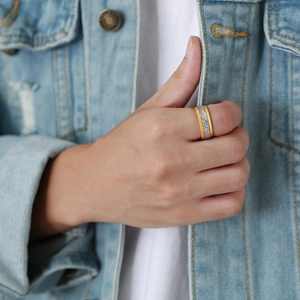 Close-up of a two-tone tungsten ring with gold edges and textured inlay on a finger