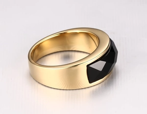 Detail of a men's wide gold-plated ring featuring a large faceted black onyx gemstone