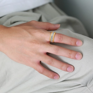 Detail of 8mm tungsten ring with gold edges and grey textured inlay on a finger