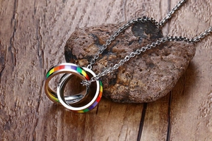 Macro detail of interlocked double ring pendant with rainbow enamel on wood and stone