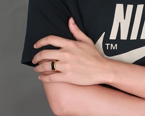 Macro shot of men's wide gold ring with black onyx inlay on model's finger