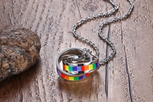 Detailed view of rainbow interlocking circles pendant on a wood and stone background