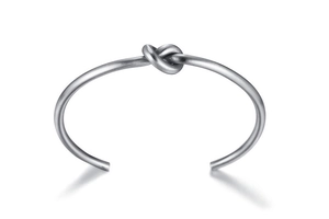 Macro shot of silver knot detail on a matte brushed titanium steel open cuff bracelet