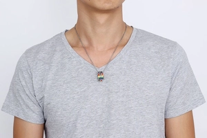Detail of man wearing double-ring rainbow pendant necklace on stainless steel chain