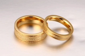 Détail de bagues de couple dorées avec finition sablée et bords polis miroir