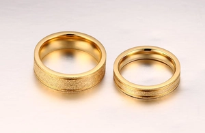 Détail de bagues de couple dorées minimalistes avec finition sablée et bords polis