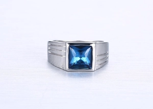Detailed macro shot of men's stainless steel ring featuring a square blue sapphire gemstone