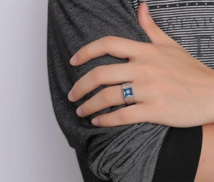 Close-up of men's wide silver band ring featuring a square step-cut blue gemstone
