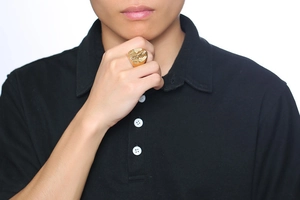 Detailed close-up of a golden Egyptian Pharaoh signet ring worn by a male model