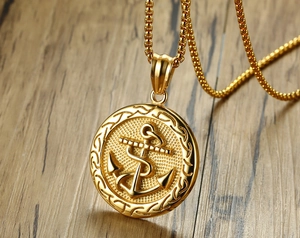 Macro view of golden anchor pendant with embossed texture and gold box chain