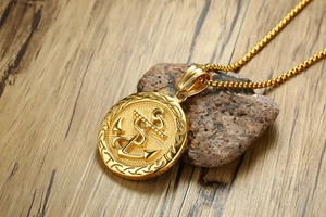 Detail of a gold anchor pendant with embossed rope border on a square bead chain
