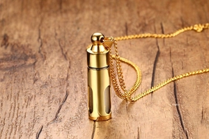 Détail macro du pendentif flacon de parfum doré avec fenêtre sur fond en bois naturel