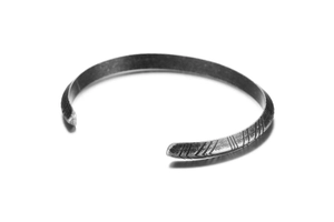 Detailed macro shot of vintage grey stainless steel cuff bracelet with arrow engravings