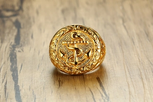 Detailed close-up of golden anchor signet ring with rope relief on a wooden background