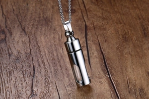 Détail macro du pendentif flacon de parfum en acier inoxydable argenté avec vitre sur bois