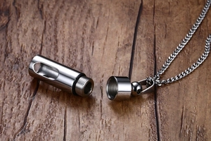 Vue macro d'un pendentif cylindre en acier inoxydable avec fenêtre et bouchon à vis