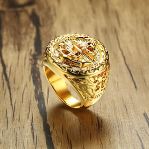 Detail of gold anchor signet ring with military crest on rustic dark wood background