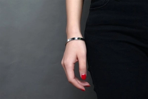 Macro shot of polished silver stainless steel C-shaped open bangle on a model wrist