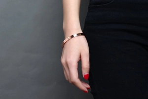 Close-up of polished rose gold 6mm stainless steel C-shaped cuff bracelet on wrist