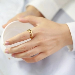 Close-up of a gold chain link ring on finger, featuring a polished oval link design
