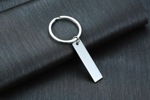 Close-up of polished silver stainless steel rectangular keychain tag on black textured background