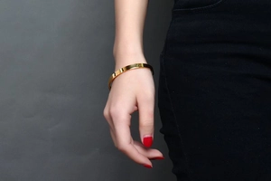 Close-up of polished 6mm gold C-shaped stainless steel cuff bracelet on a female wrist