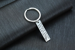 Detailed close-up of engraved rectangular stainless steel keychain with quote and heart icons