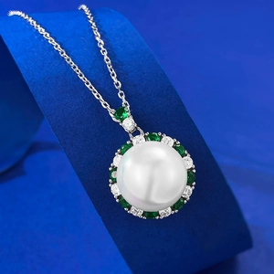Elegant 12mm pearl necklace with emerald green gemstone halo pendant on blue stand