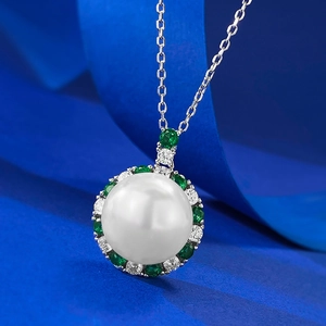 Elegant 12mm pearl necklace with emerald and diamond cluster pendant on blue silk