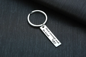 Macro shot of stainless steel keychain engraved with Have courage and be kind text