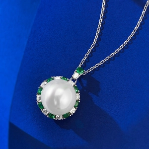 Luxury 12mm pearl necklace with emerald and diamond halo on a navy display base
