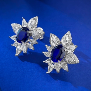 Close-up of S925 silver flower stud earrings with 2ct oval blue sapphire and zircon petals