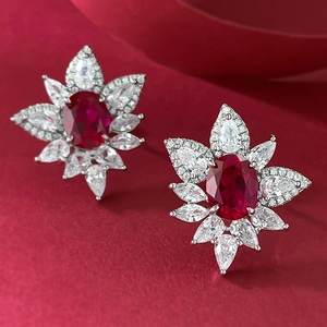 Macro shot of silver cluster earrings with oval red ruby and marquise zircon petals
