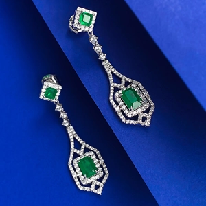 Macro view of emerald-cut green gemstone earrings with sparkling pavé zircon accents