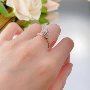 Close-up of rose gold flower ring with center diamond and twisted band on a hand